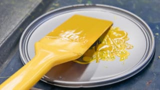 Pinsel mit gelber Farbe auf einem Farbdeckel von ökologischer Farbe für Bogendruck bei der Sternsche Druckerei