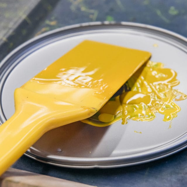 Pinsel mit gelber Farbe auf einem Farbdeckel von ökologischer Farbe für Bogendruck bei der Sternsche Druckerei