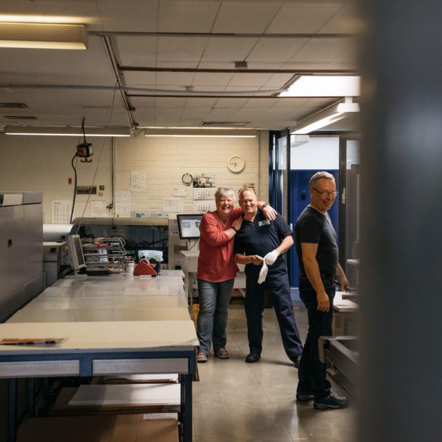 Lachende Mitarbeiter in der Vorstufe: Teamarbeit in der Druckerei von Stern'sche in Lüneburg