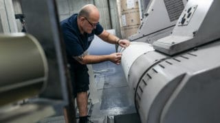 Mitarbeiter im Zeitungsdruck bei der von Stern'sche Druckerei in Lüneburg bereitet Papierrolle vor