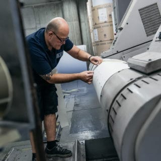 Mitarbeiter im Zeitungsdruck bei der von Stern'sche Druckerei in Lüneburg bereitet Papierrolle vor